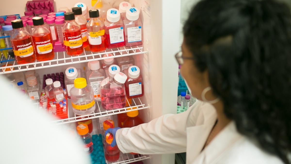 a person looking into a refrigerator full of liquids in bottles with labels